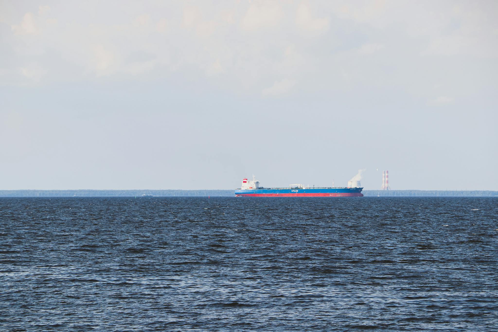 A cargo ship sails on a calm ocean under a clear sky. Ideal for transport and maritime themes.