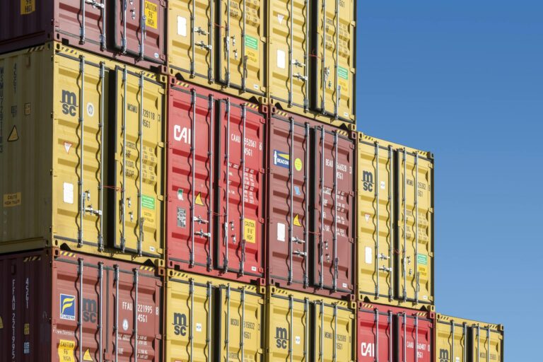 Colorful shipping containers stacked against a clear blue sky, representing global trade and transportation.
